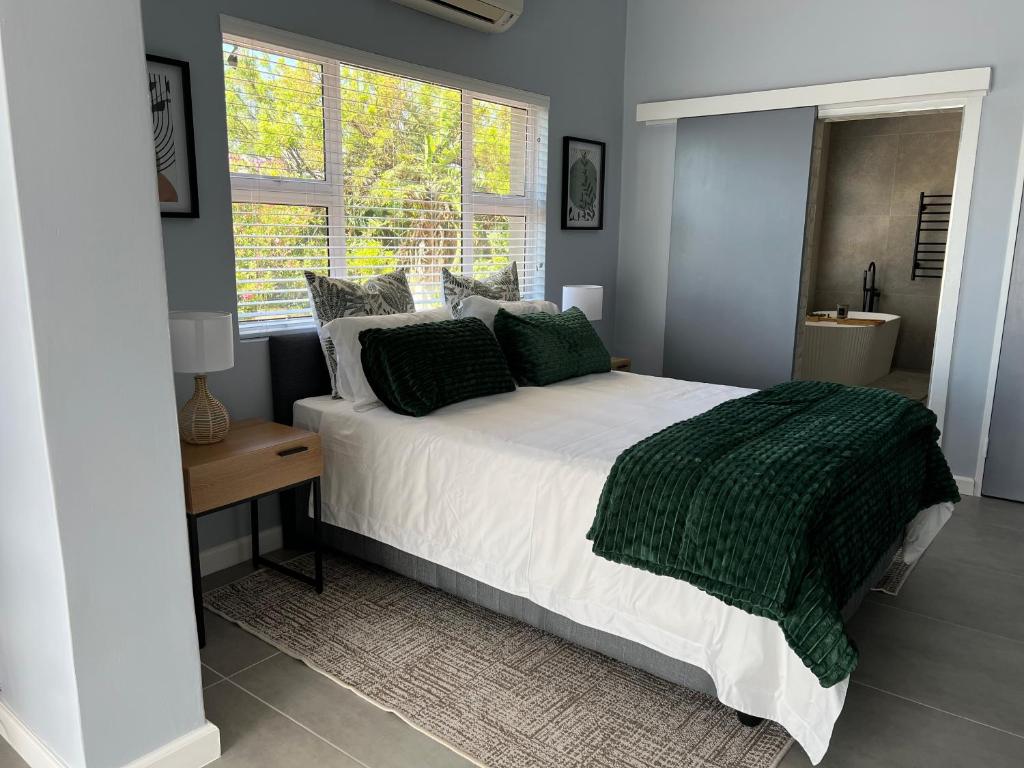 Double bedroom with white linen, a green throw and a window beside the bed